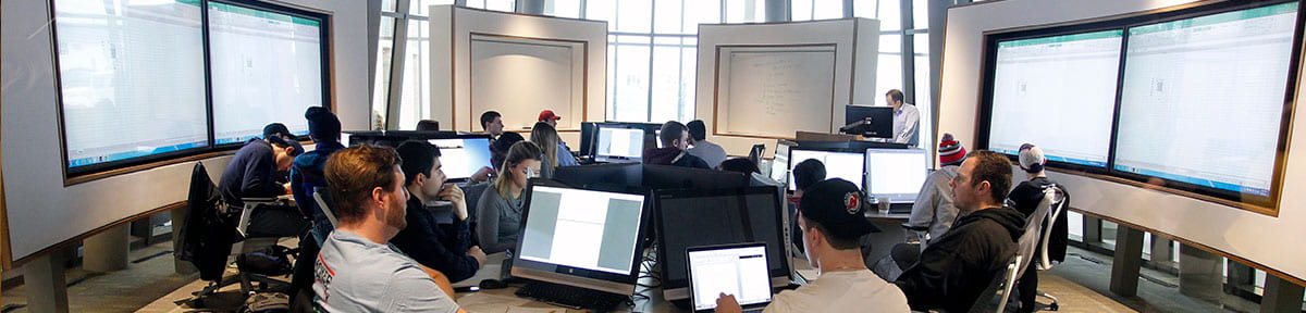 Students surrounded by LED screens in a business school classroom