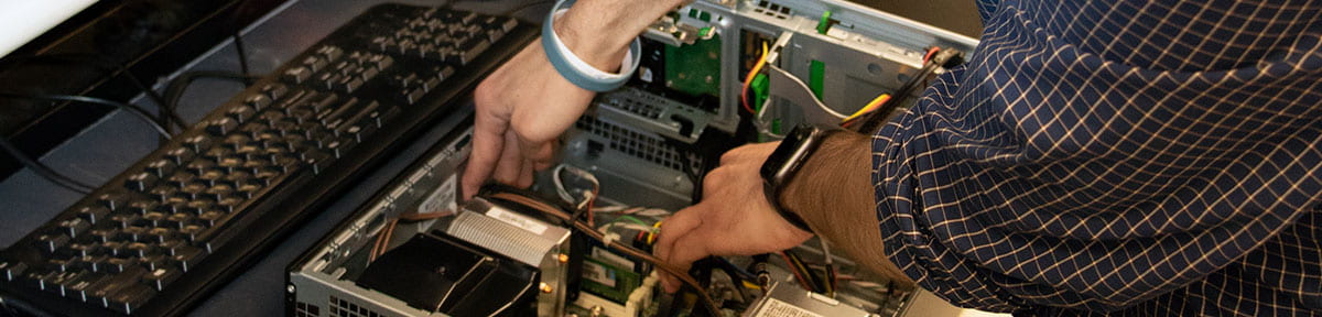 Close-up image of the hands of a technician replacing the hard drive in a desktop computer